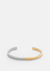 Skultuna SB Cuff Thin in two-tone steel and gold, showcasing a sleek, minimalist accessory with a polished finish.