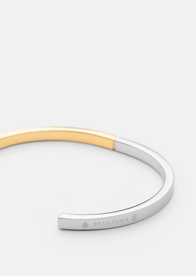 Skultuna SB Cuff Thin in two-tone steel and gold, a sleek accessory with a modern, minimalist design.