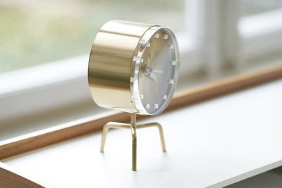 Vitra Tripod Desk Clock accessory with sleek design, featuring a tripod stand and minimalist clock face on a workspace surface.