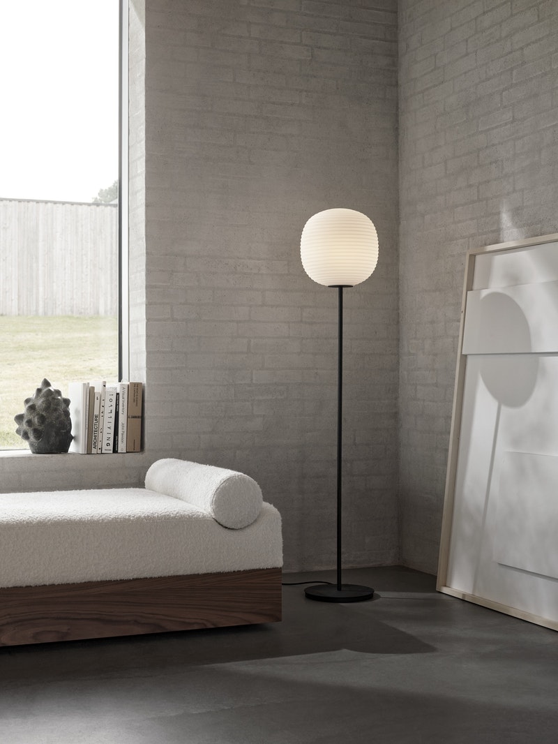 Elegant lantern-style floor lamp by New Works with a sleek design and warm lighting for modern living spaces.